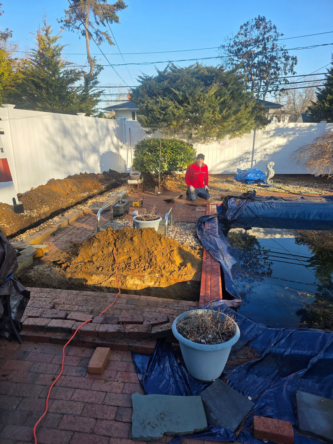 In-ground pool plumbing renovation showing new PVC lines being trenched and installed in a backyard during pre-season maintenance.