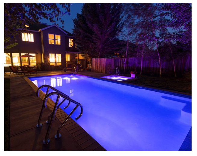 S.R. Smith Treo LED color-changing pool lights illuminating a backyard swimming pool at night.